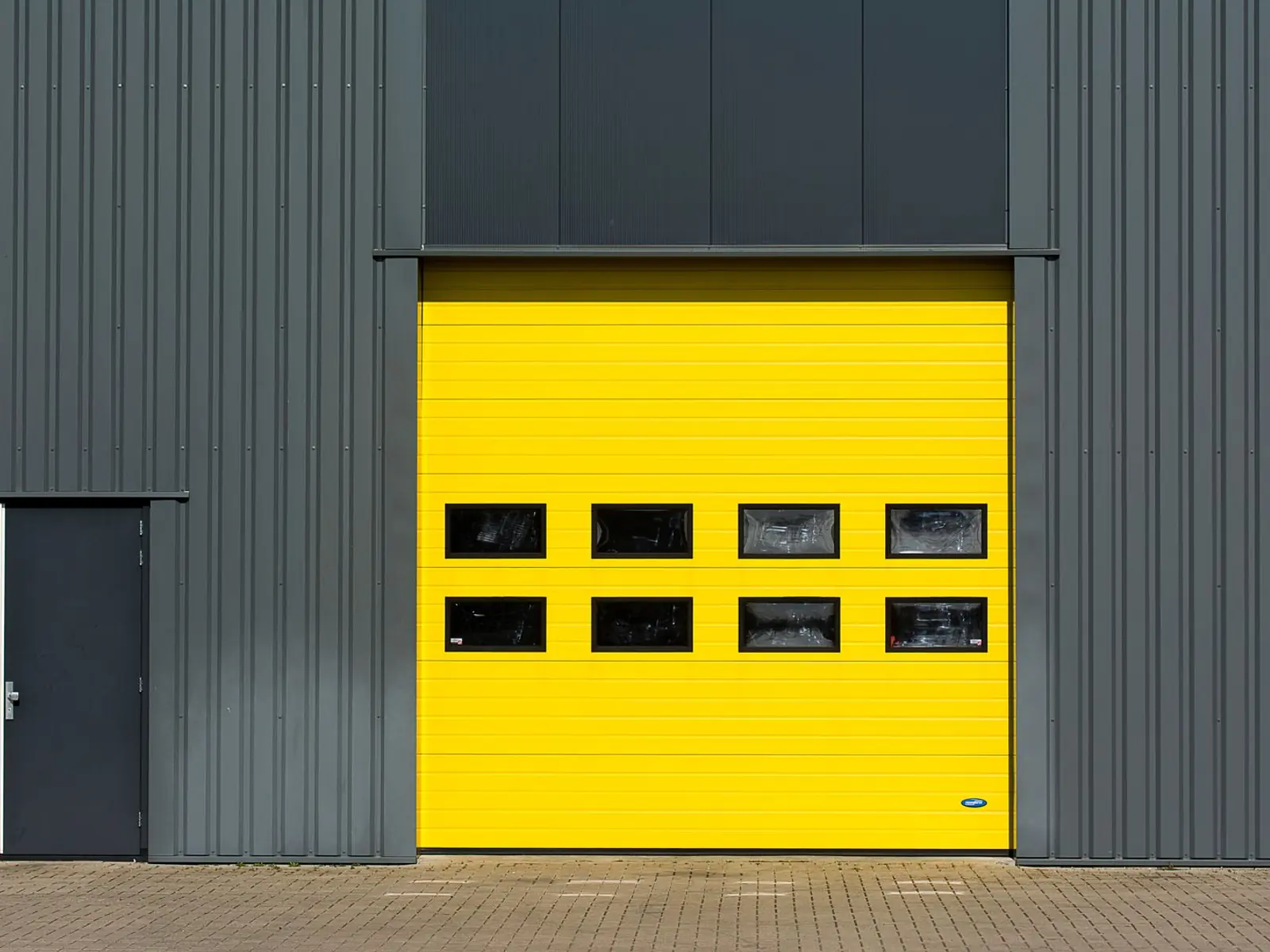 Portón amarillo de carga en la fachada de chapa de una nave industrial