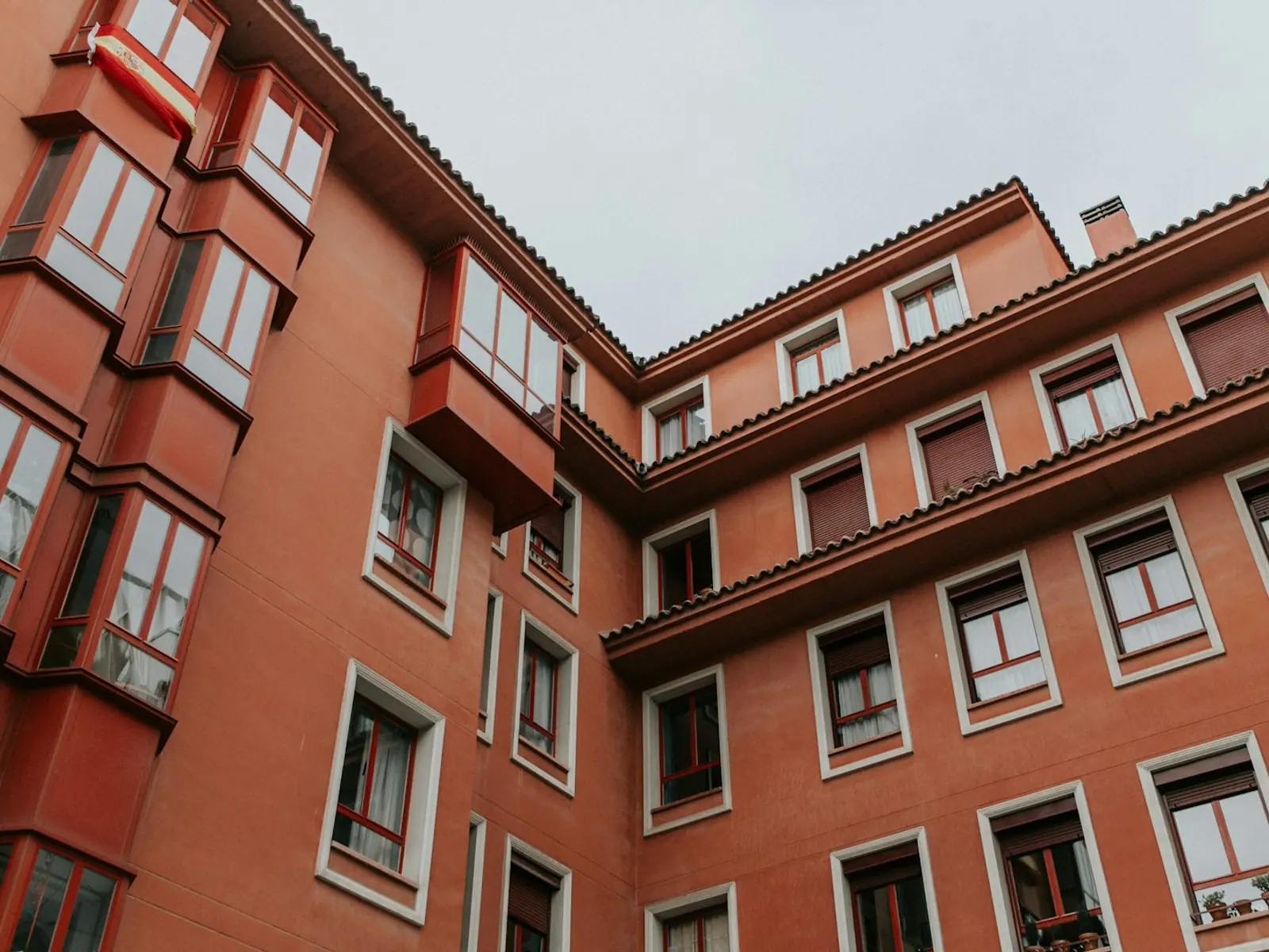 Edificio de viviendas visto desde la calle, con miradores y persianas