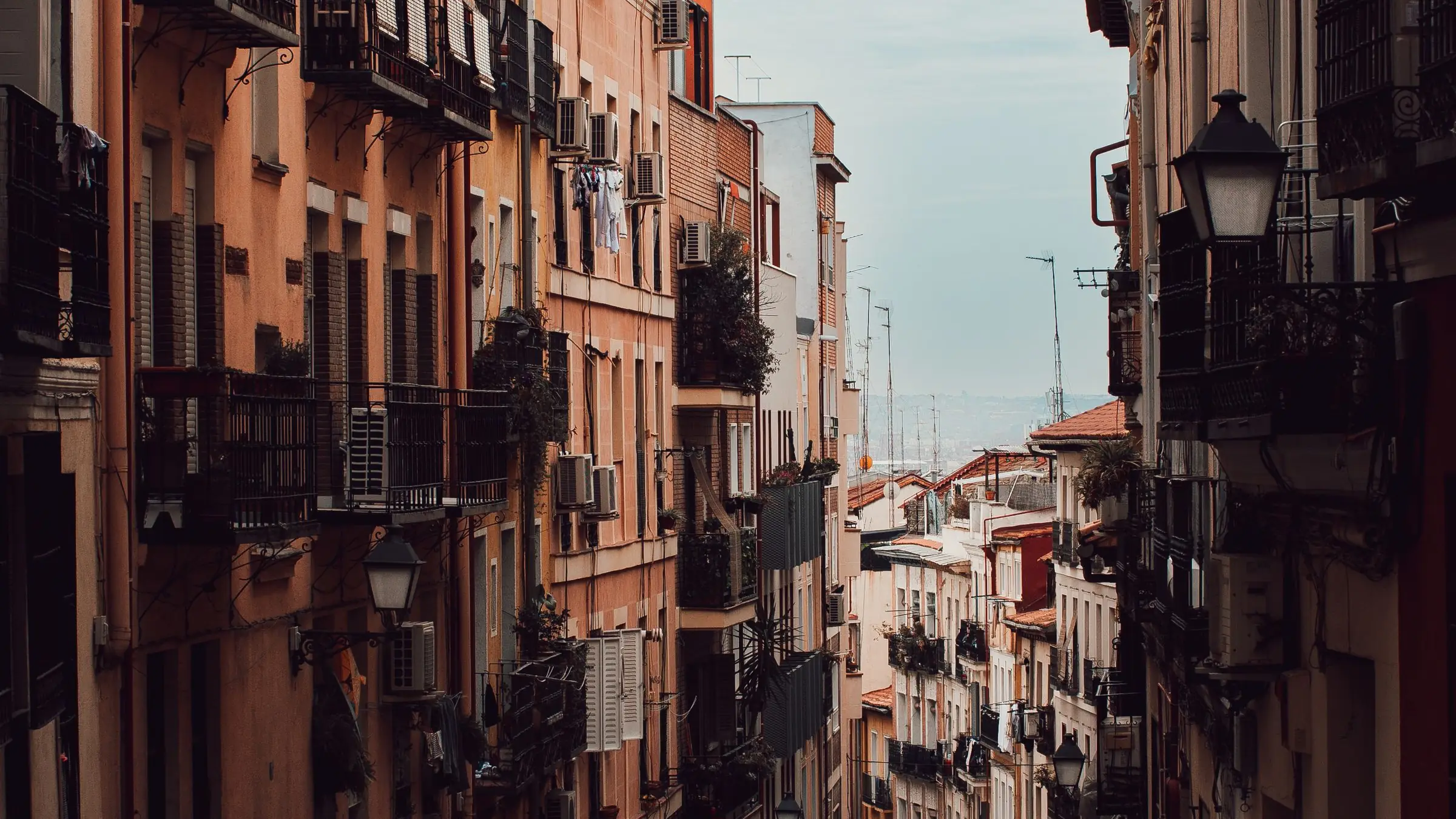 Calle de un barrio de Madrid con bloques de viviendas, balcones y farolas